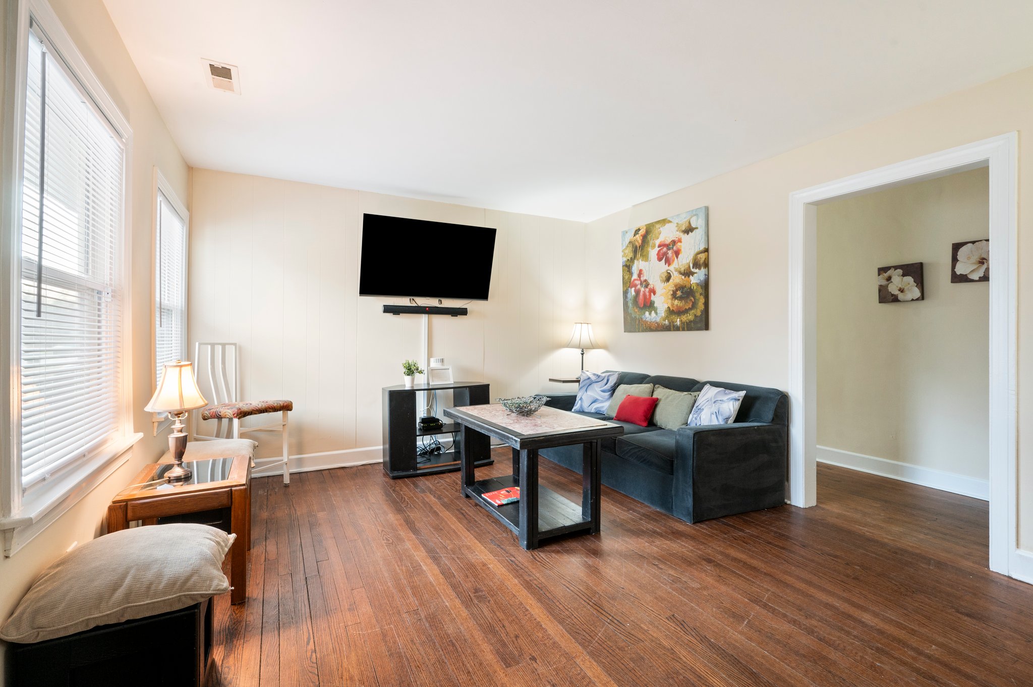 Bright living room with blue couch, mounted TV, and artwork on the wall.
