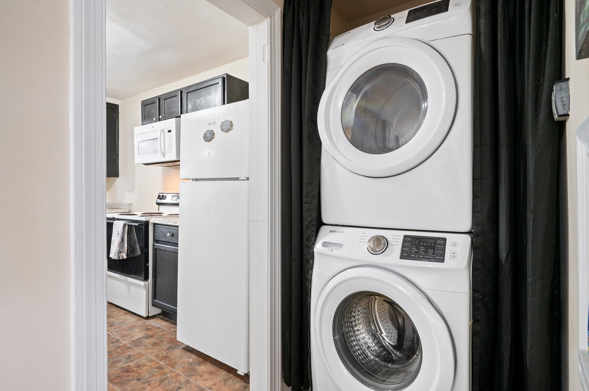 Laundry area with stacked washer and dryer next to the kitchen.
