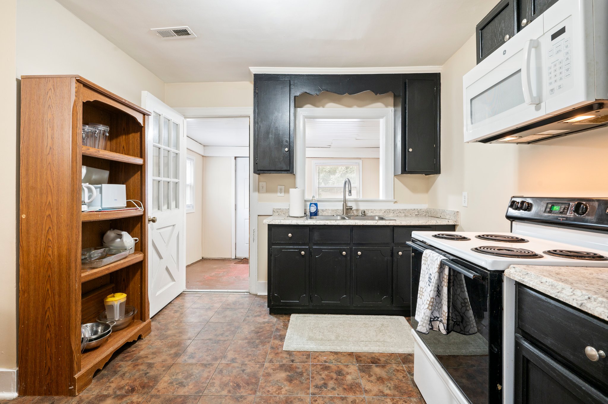 Kitchen with black cabinets, white appliances, and a tiled floor.