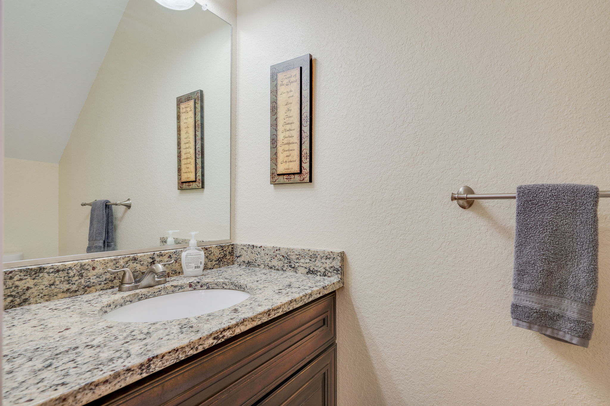 Bathroom with granite countertop, dark wood vanity, and a large mirror.