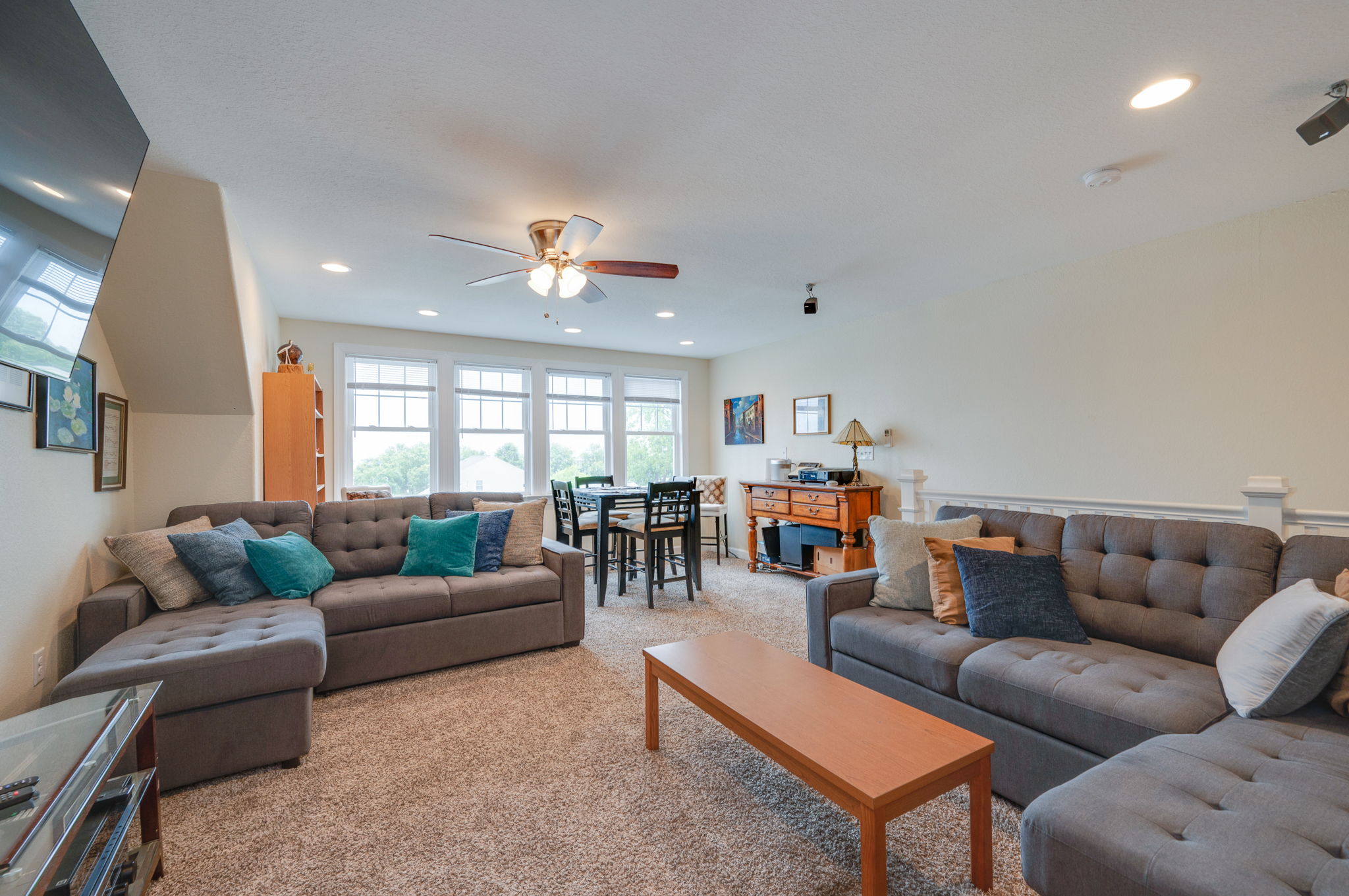 Spacious loft living area with gray sofas, decorative pillows, and a dining space.