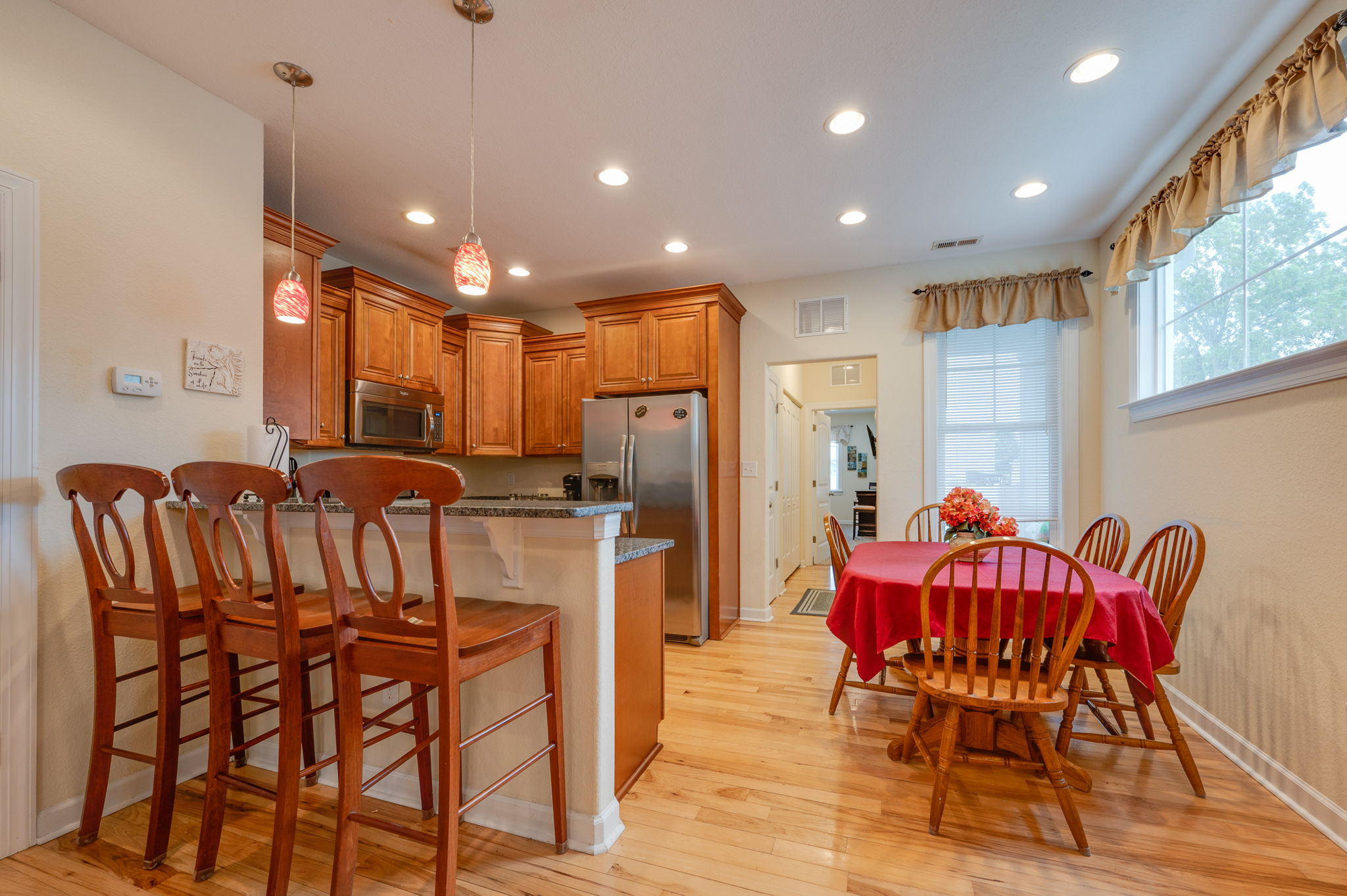 Dining area with a red tablecloth and large windows bringing in natural light.