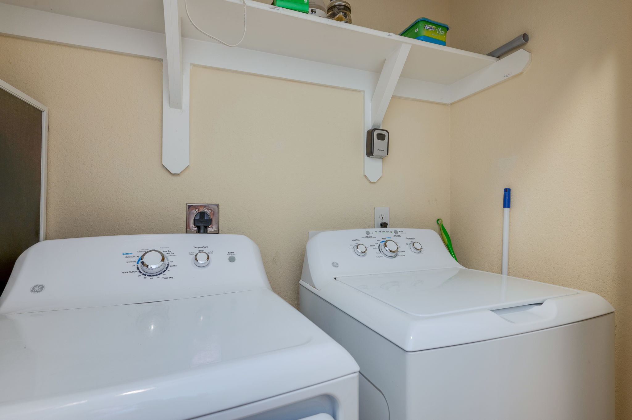 Compact laundry room with a washer and dryer, featuring storage shelves.