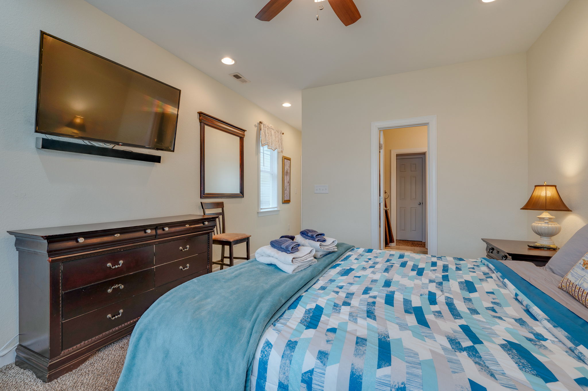 Bedroom with a mounted TV, dresser, and comfortable bedding for relaxation.