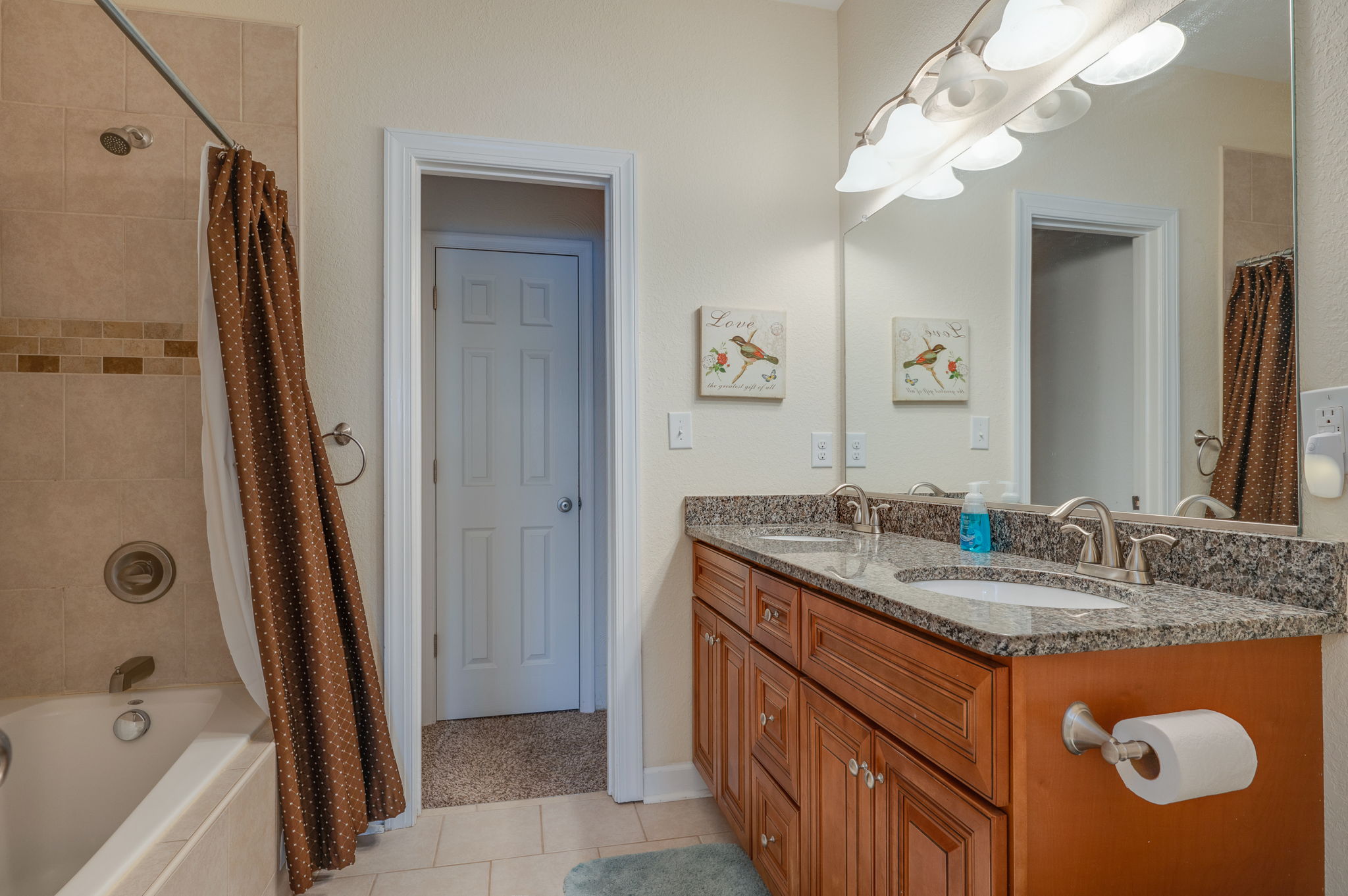 Spacious bathroom with a double vanity, granite countertops, and a bathtub.