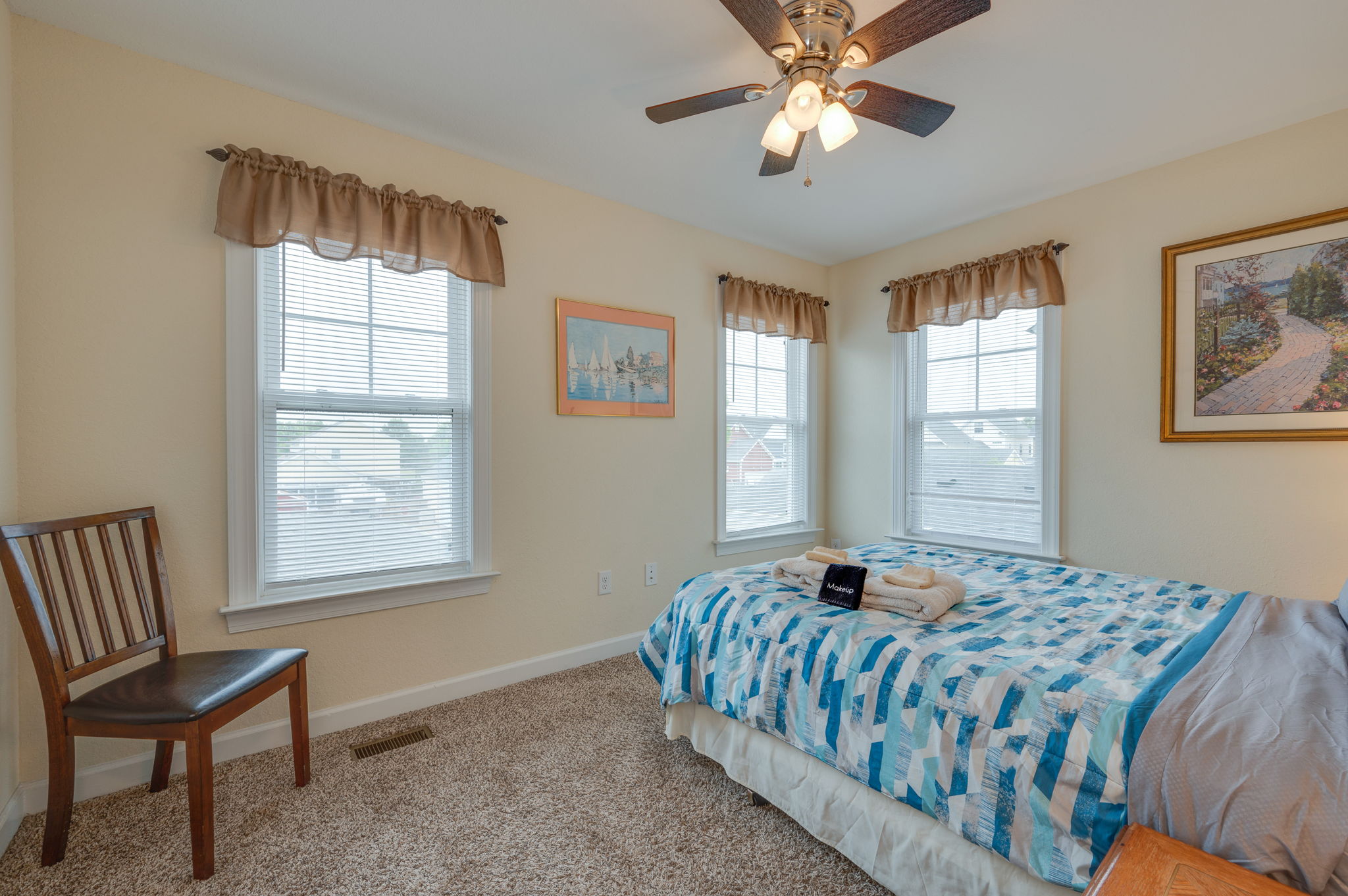 Bright bedroom with a large bed, natural light, and scenic wall art.