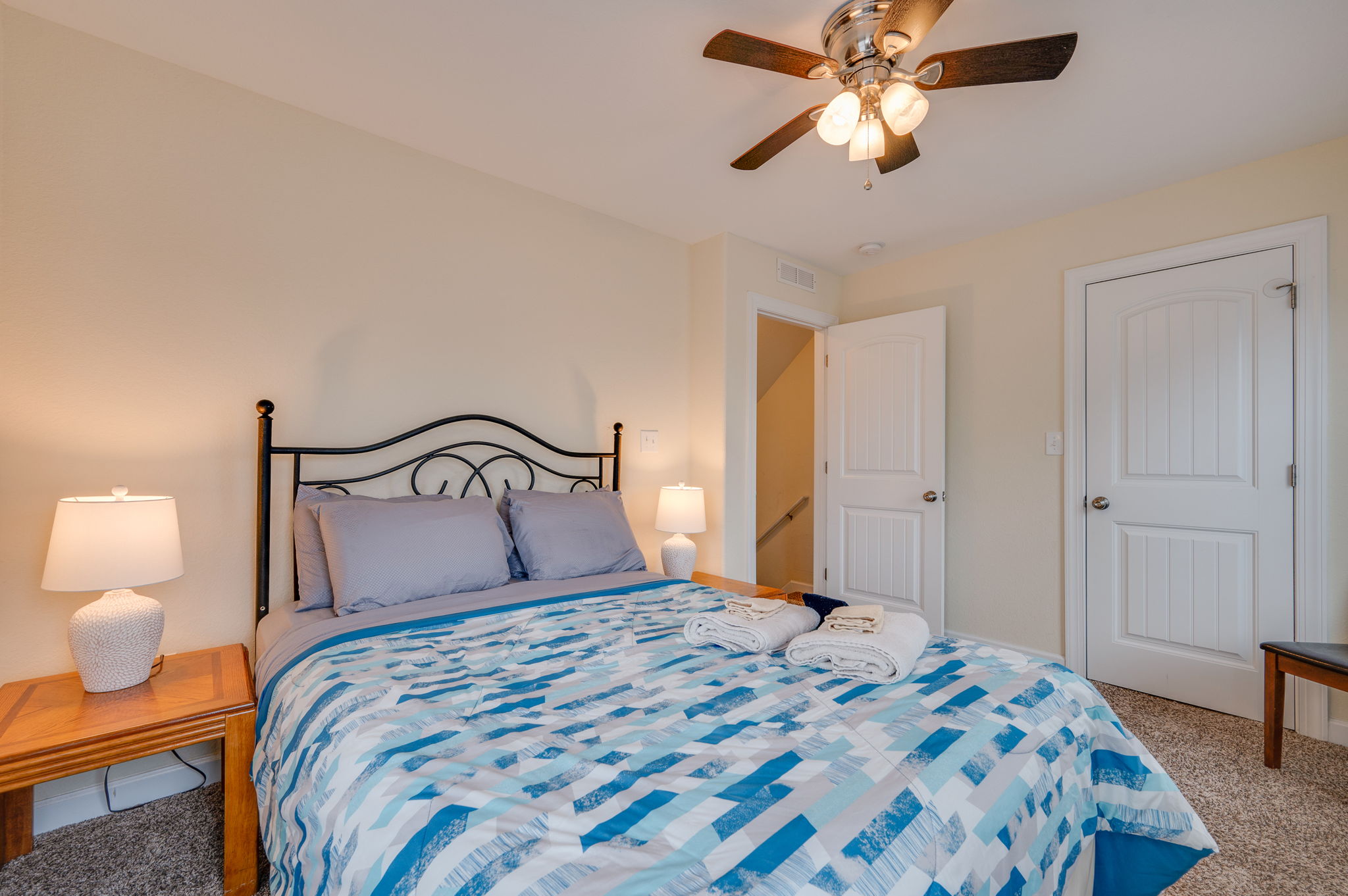 Stylish bedroom with soft bedding, a ceiling fan, and neutral wall colors.