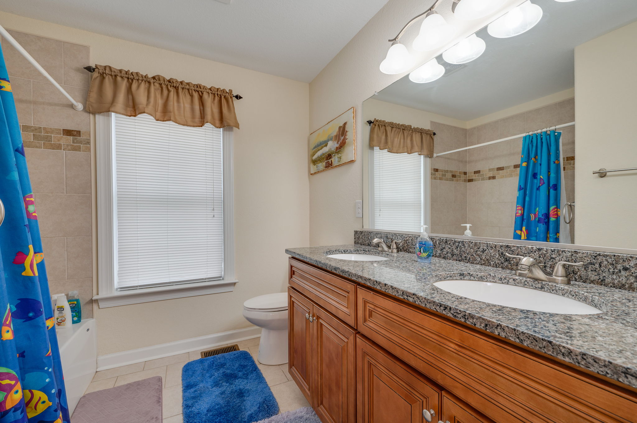 Kid-friendly bathroom with a fun ocean-themed shower curtain and double sinks.