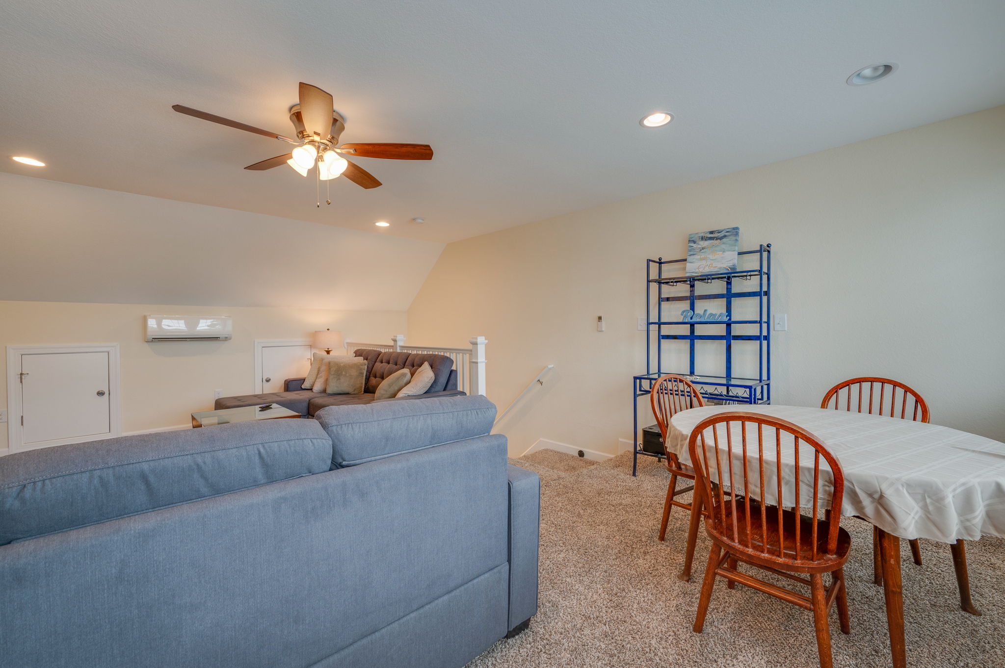 Upstairs loft with a plush sectional sofa, dining area, and soft lighting.