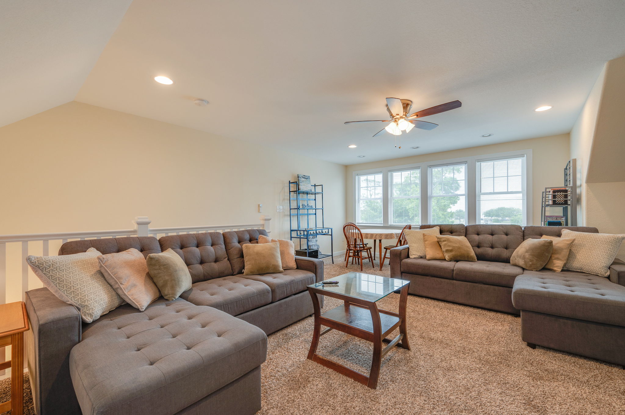 Bright and airy loft area with large windows, plush seating, and a dining table.