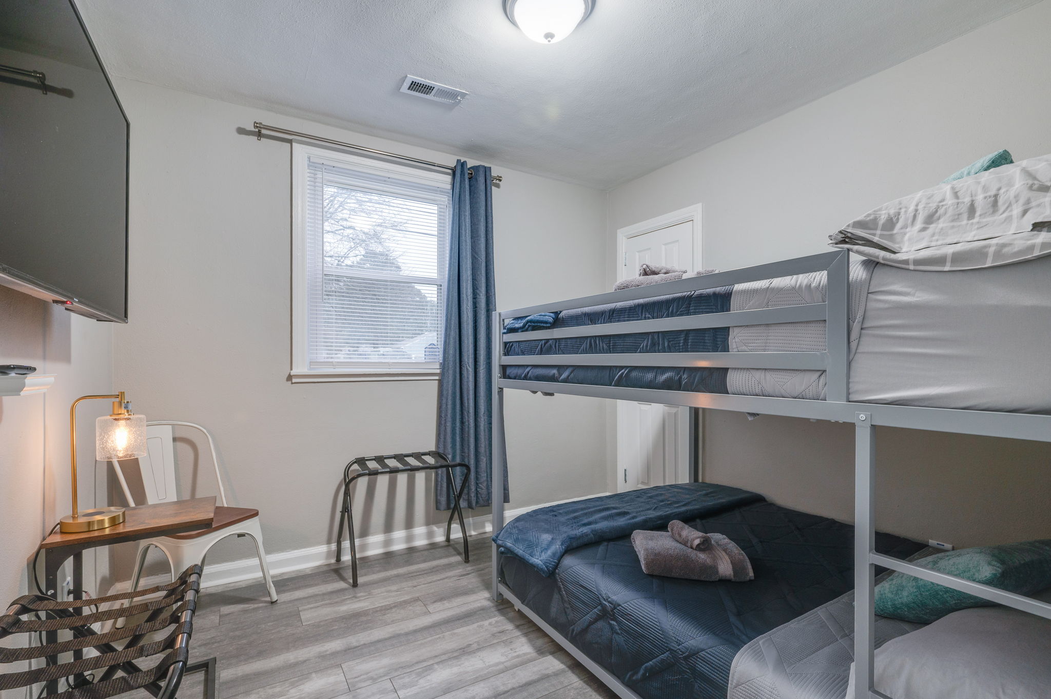 Bedroom with a bunk bed, blue bedding, and a wall-mounted TV.