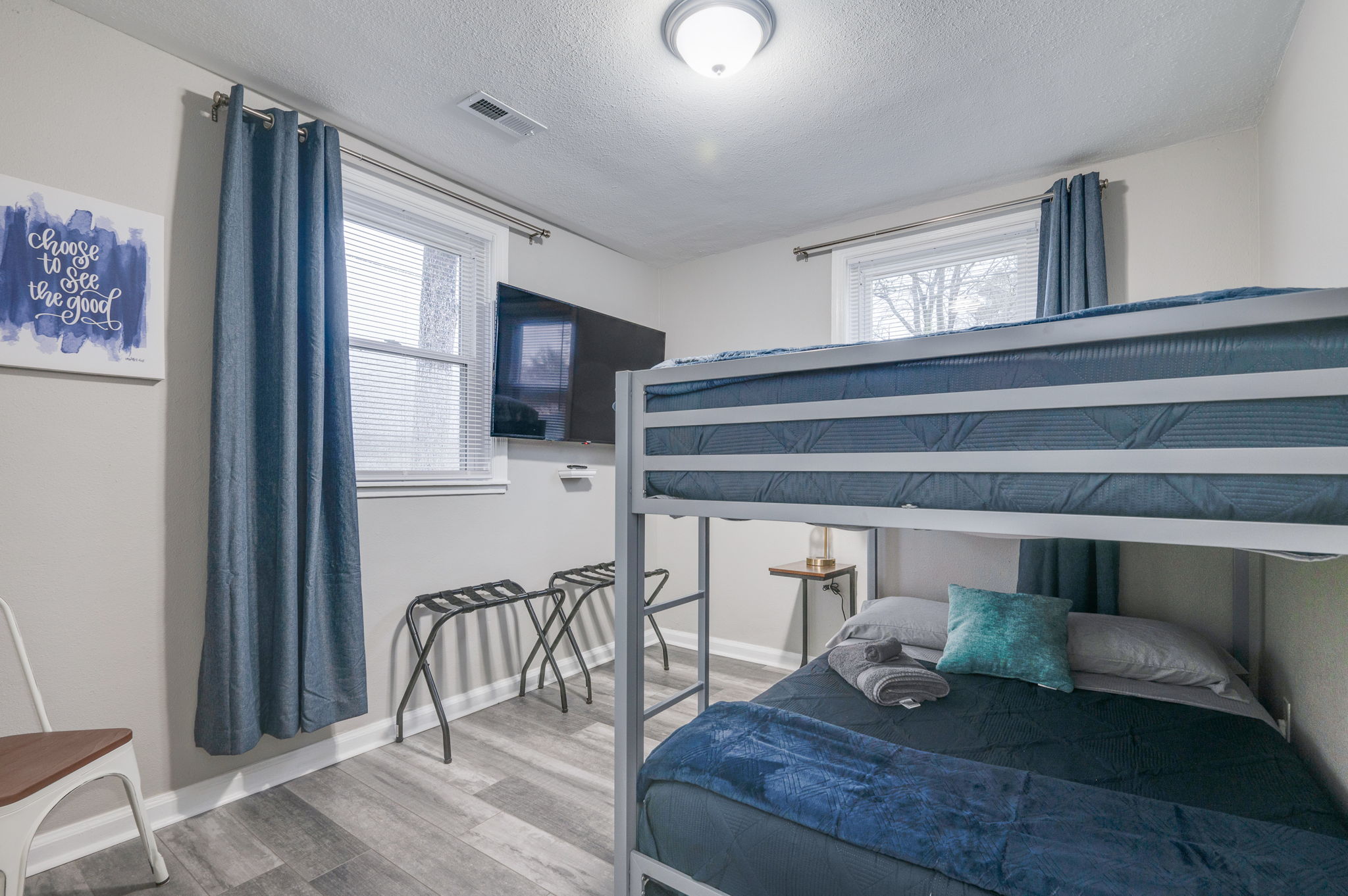 Cozy bedroom with a bunk bed, blue bedding, and a mounted TV.