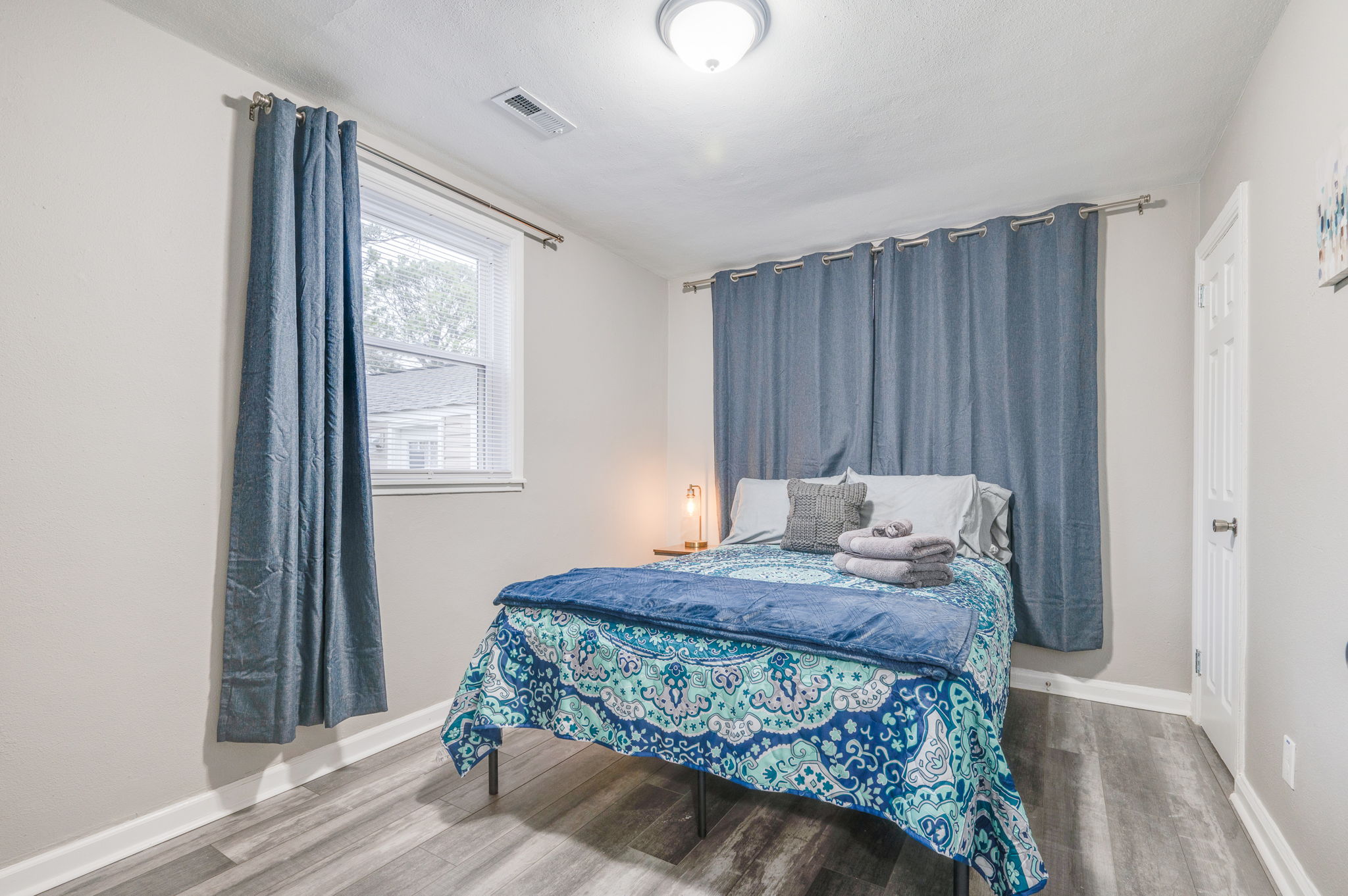 Comfortable bedroom with a full-sized bed, blue bedding, and soft lighting.