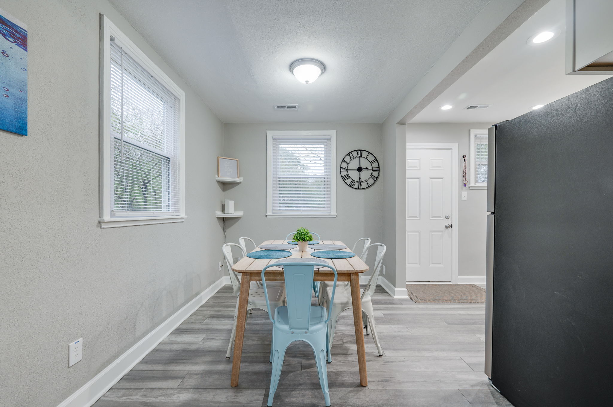Dining area with a wooden table, metal chairs, and large wall clock.