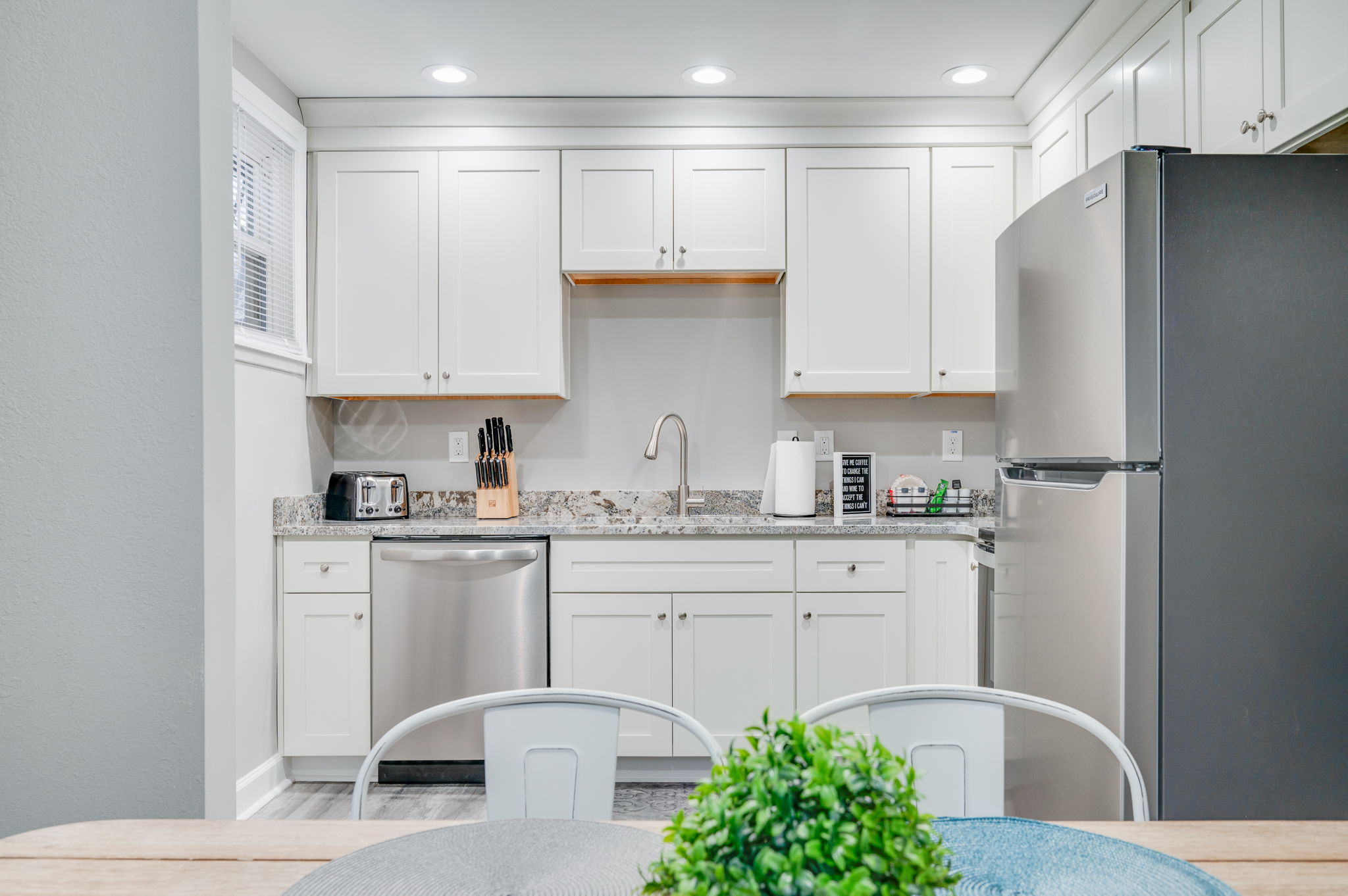 Modern kitchen with white cabinetry, stainless steel fridge, and electric stove.
