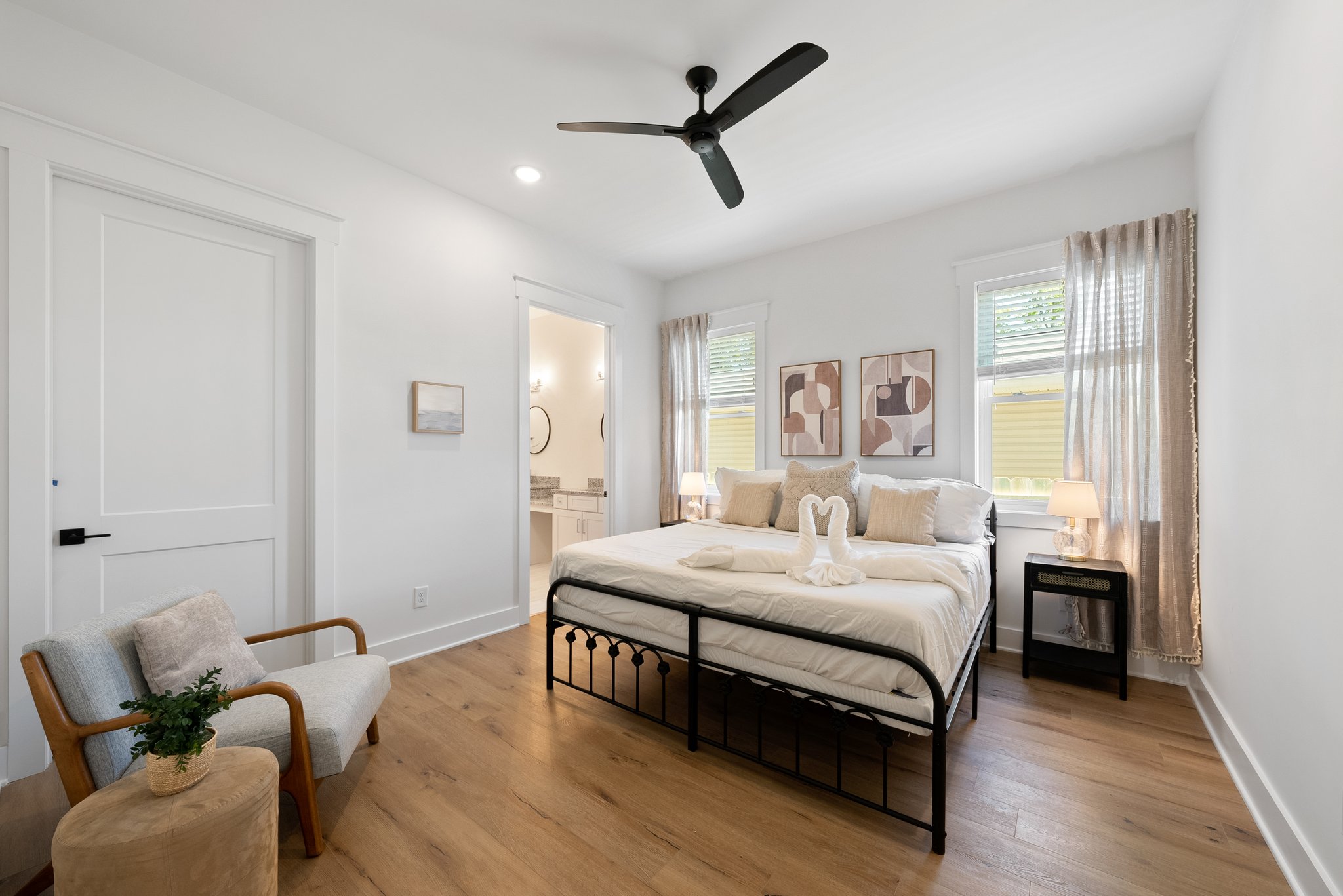 Elegant bedroom with a king-sized bed, modern decor, and an ensuite bathroom with double vanity.