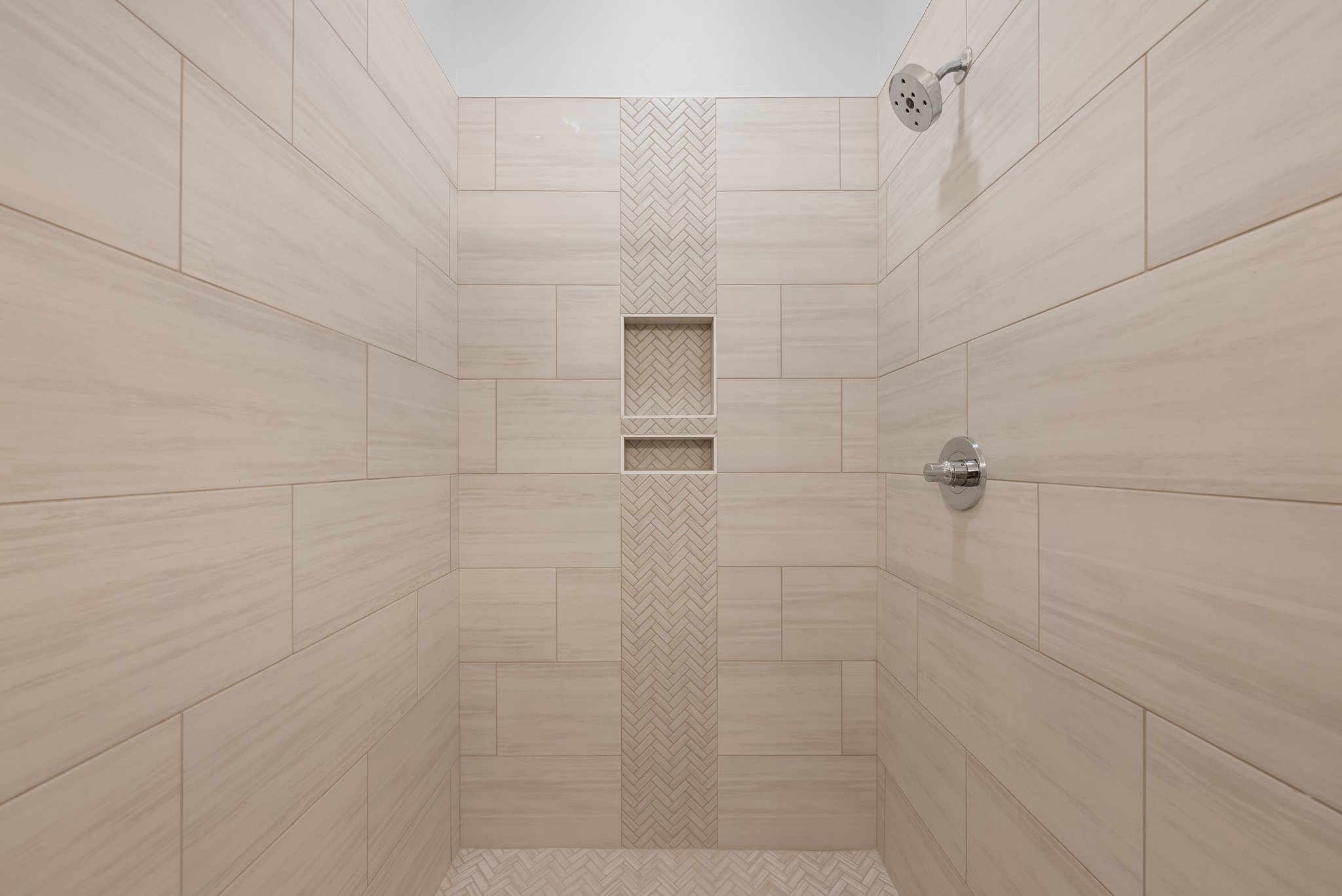 Stylish walk-in shower with beige subway tiles and a built-in niche for storage.