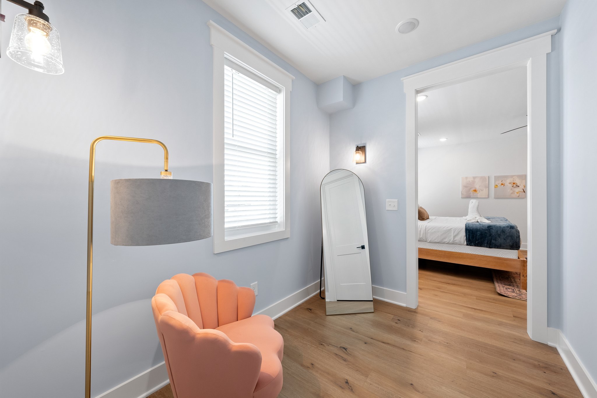 Cozy nook with pink chair, gold lamp, and floor-length mirror