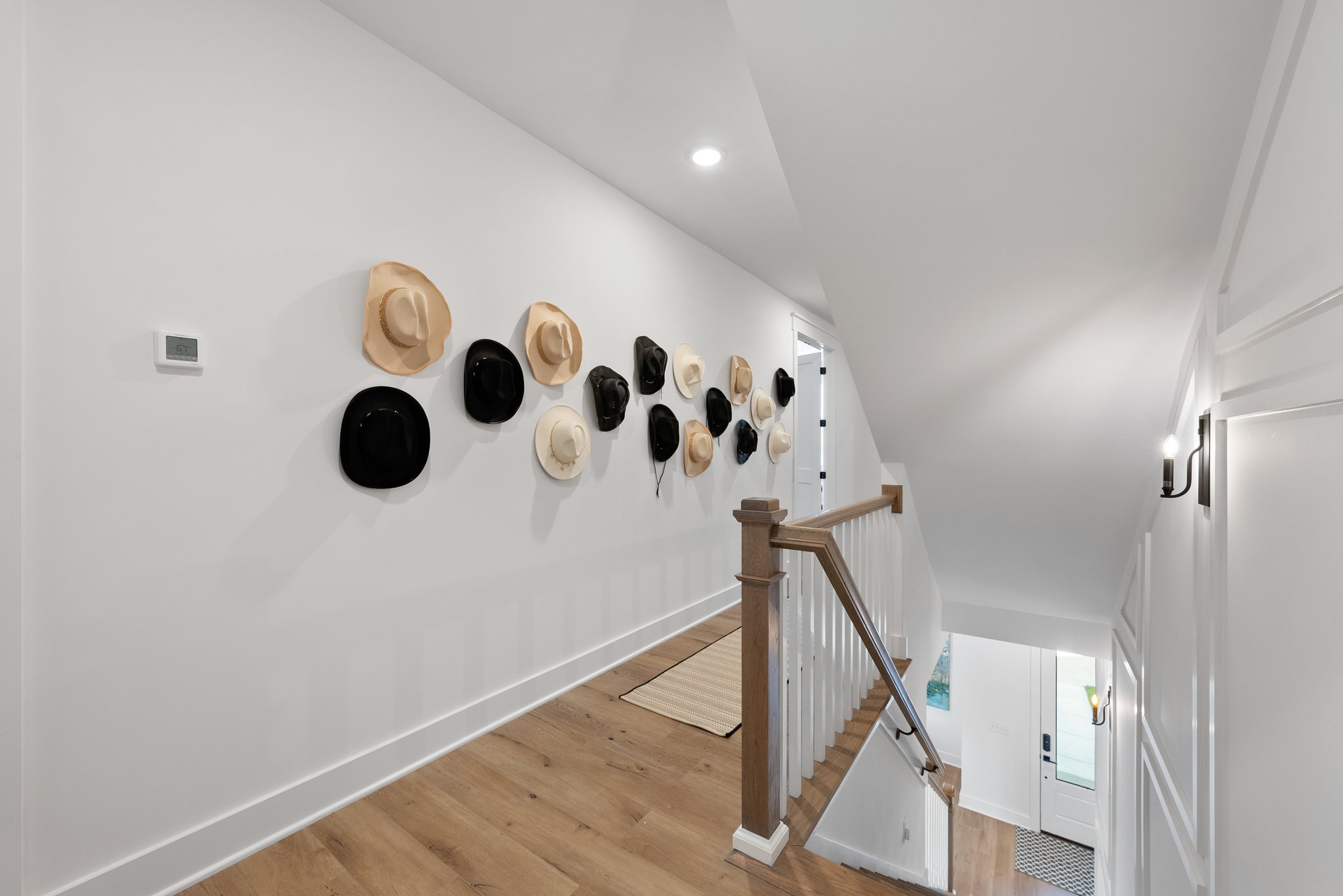 Decorative wall with hats displayed along an upstairs hallway