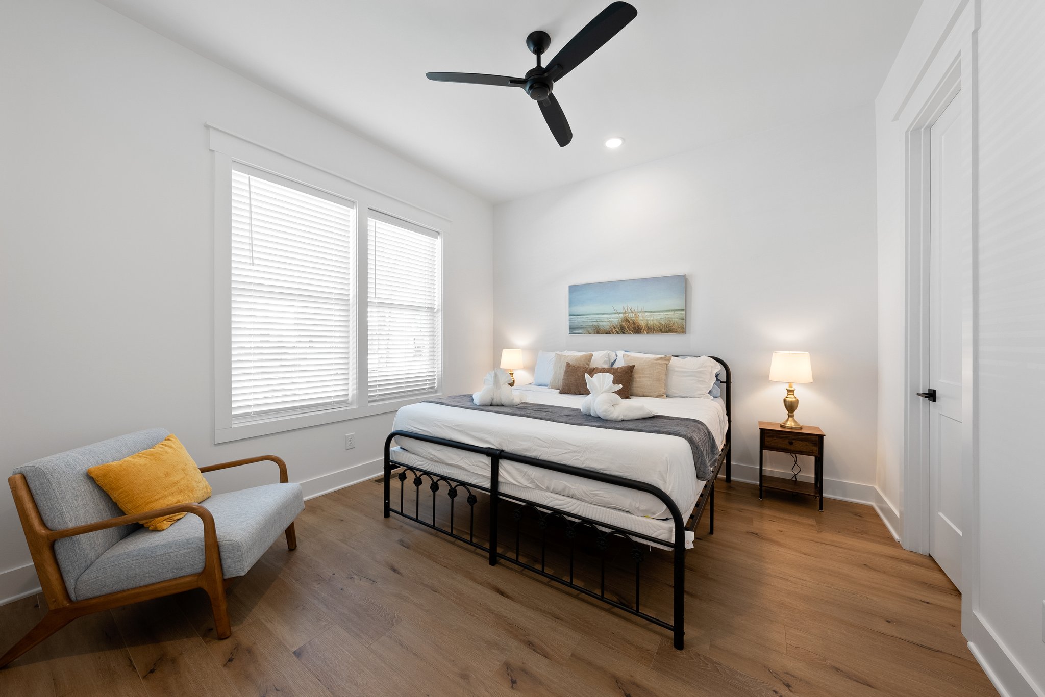 Bright and airy bedroom with a king-sized bed, modern decor, and natural light from large windows.