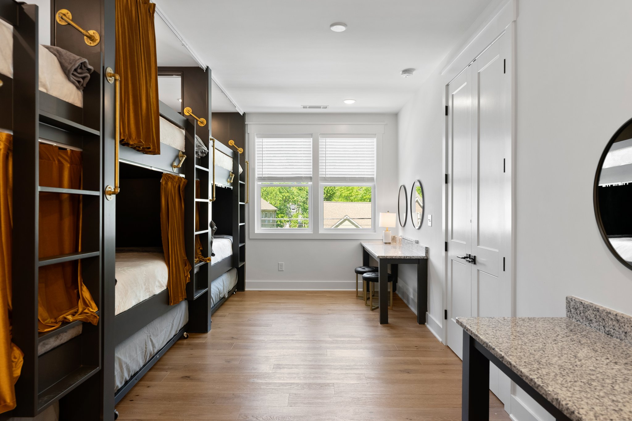A second perspective of the bunk bedroom, highlighting the large window, built-in desk, and bunk beds with privacy curtains.