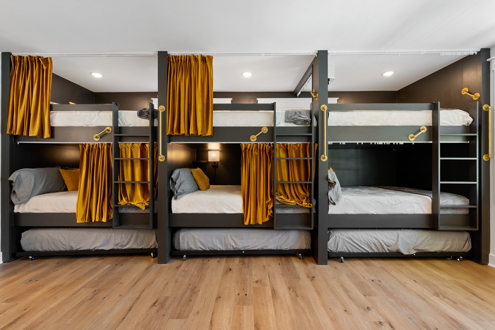 A front-facing view of the bunk beds with mustard gold curtains, dark wood frames, and built-in lighting.
