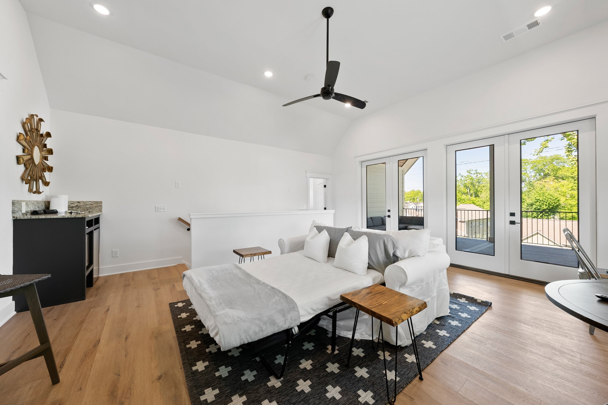 A different angle of the loft, showing a kitchenette, modern decor, and a black and white patterned rug.