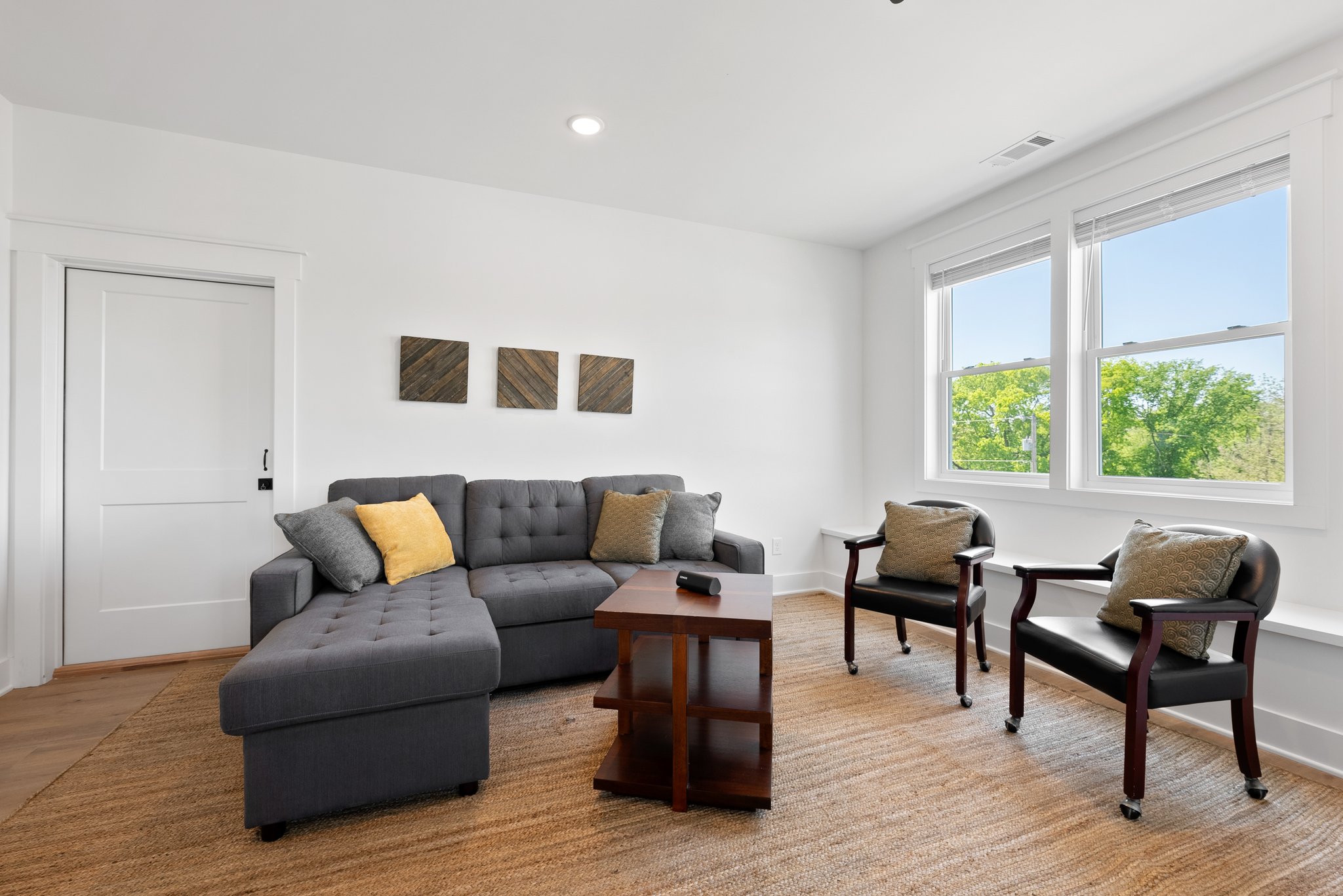 A bright and inviting sitting area with a large window, gray sectional, and decorative throw pillows.