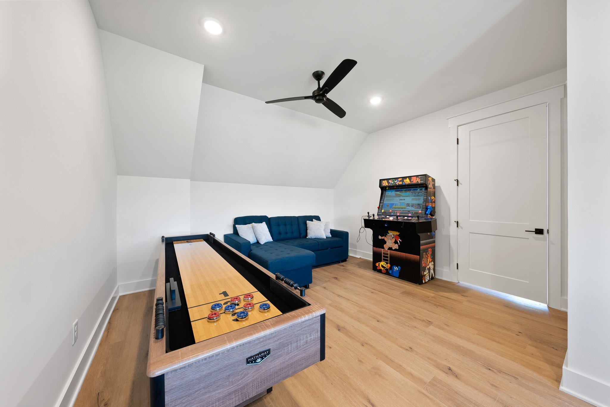 Game Room with Shuffleboard Table, Arcade Machine, and Blue Couch
