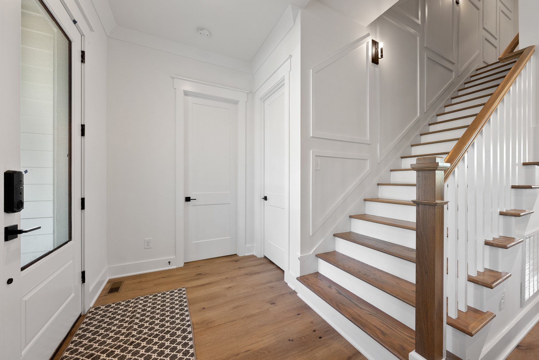 Elegant entryway with a wooden staircase leading up from the first floor.