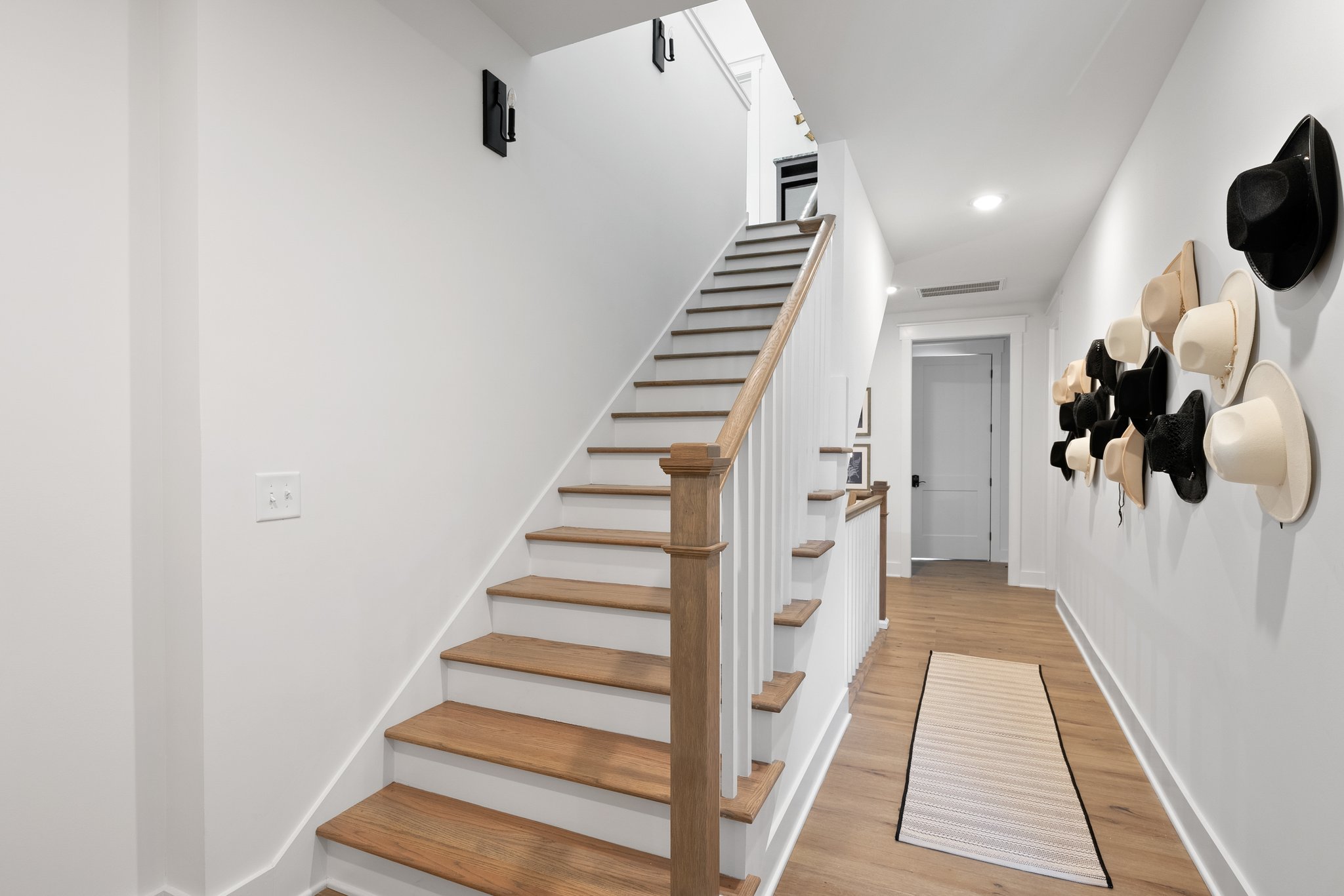 Stylish second floor staircase with wooden railings, and an artistic hat display.