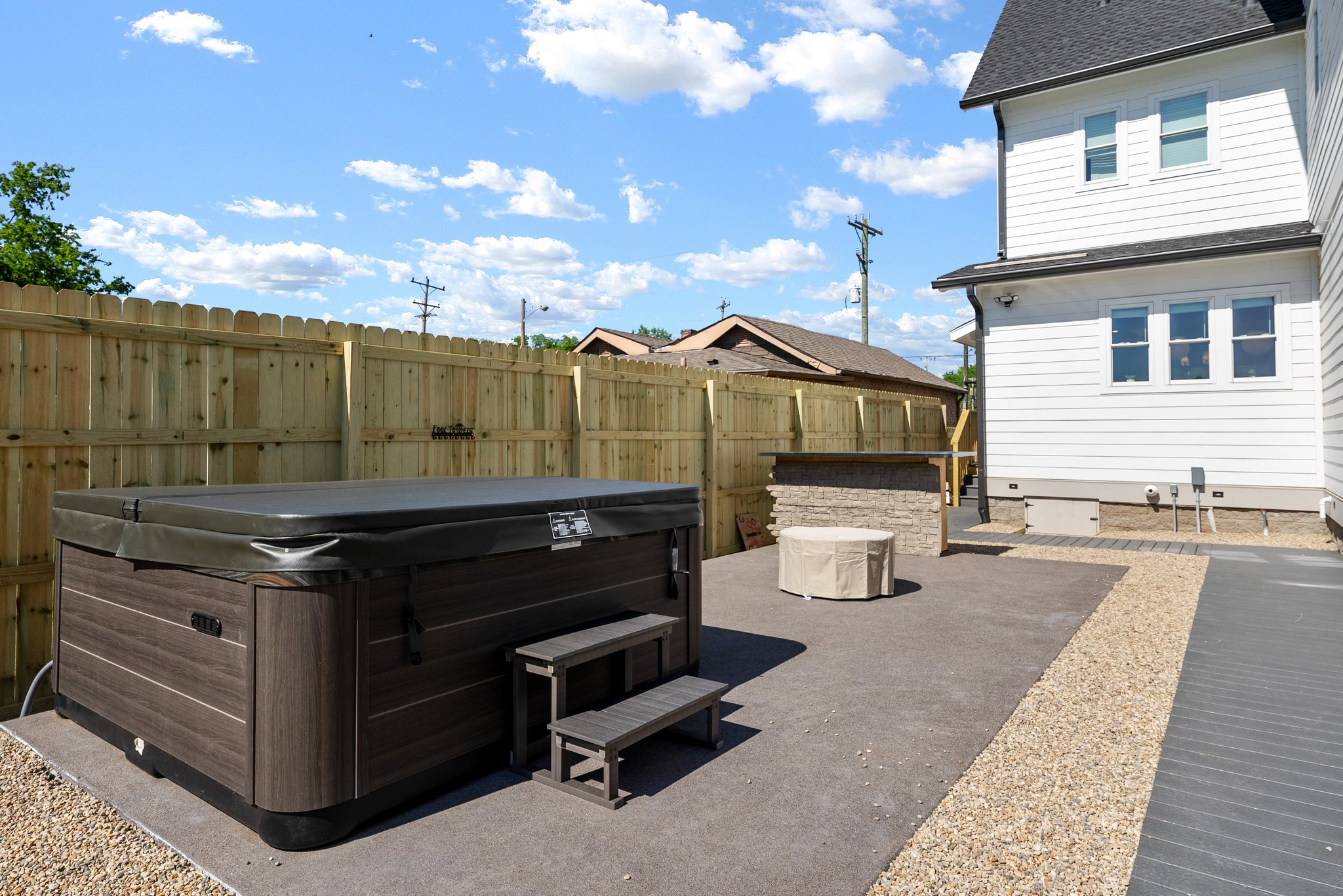 Outdoor backyard featuring a large hot tub, fire pit, and privacy fence.