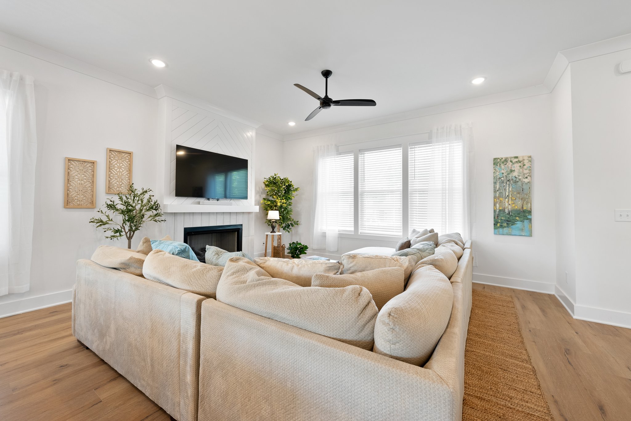 Open-concept living room with a plush sectional couch, modern decor, and bright natural lighting.