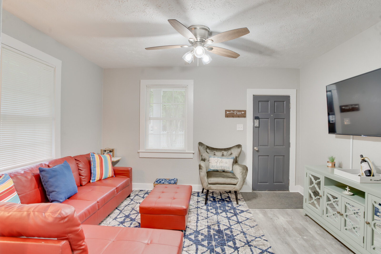 Spacious living room with mounted TV, red sofa, and accent chair