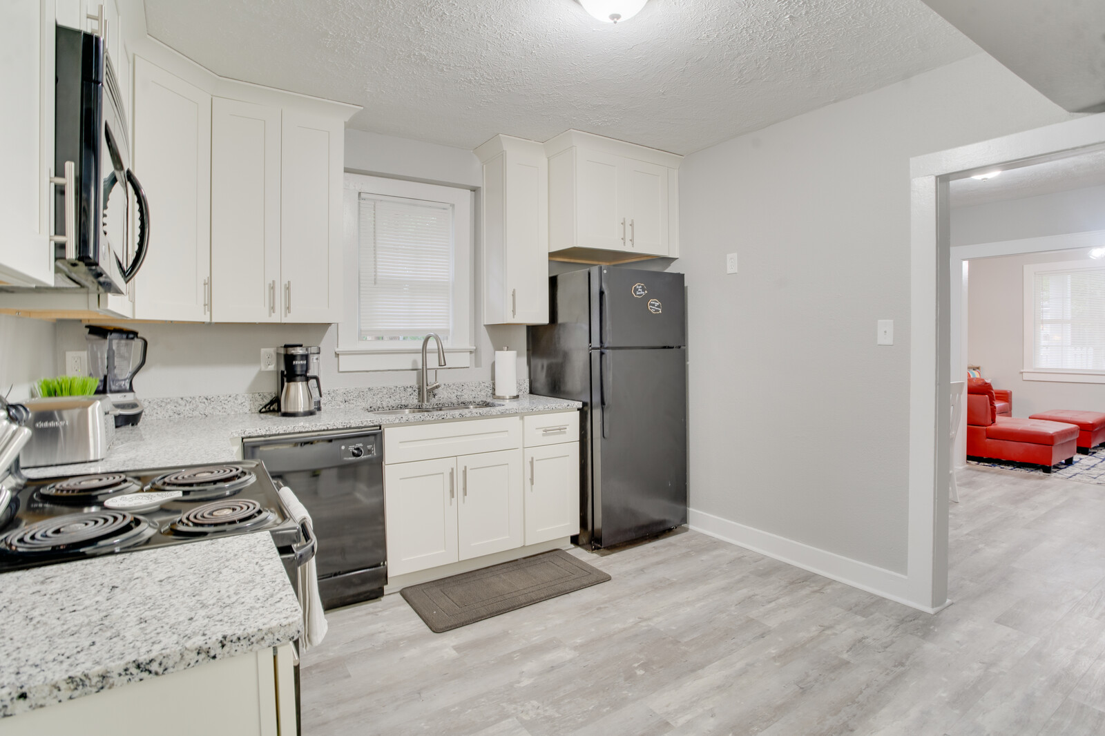 Contemporary kitchen with black refrigerator, white cabinets, and open layout