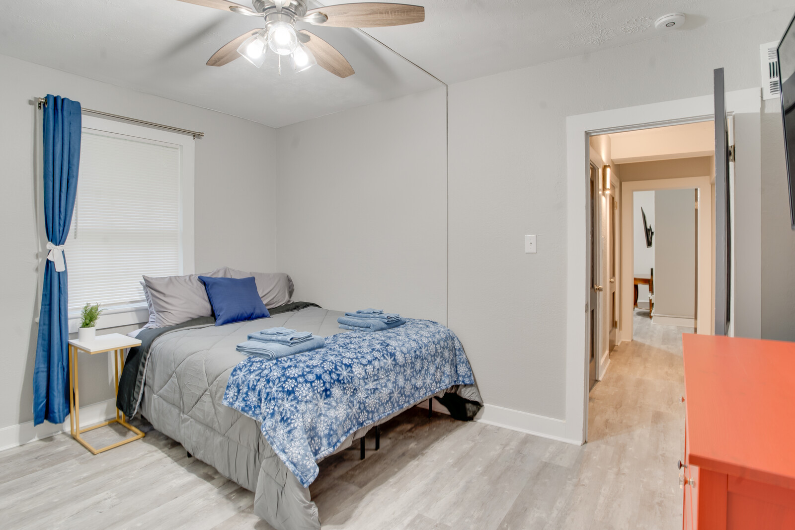 Bedroom with gray bedding, blue accents, and ceiling fan