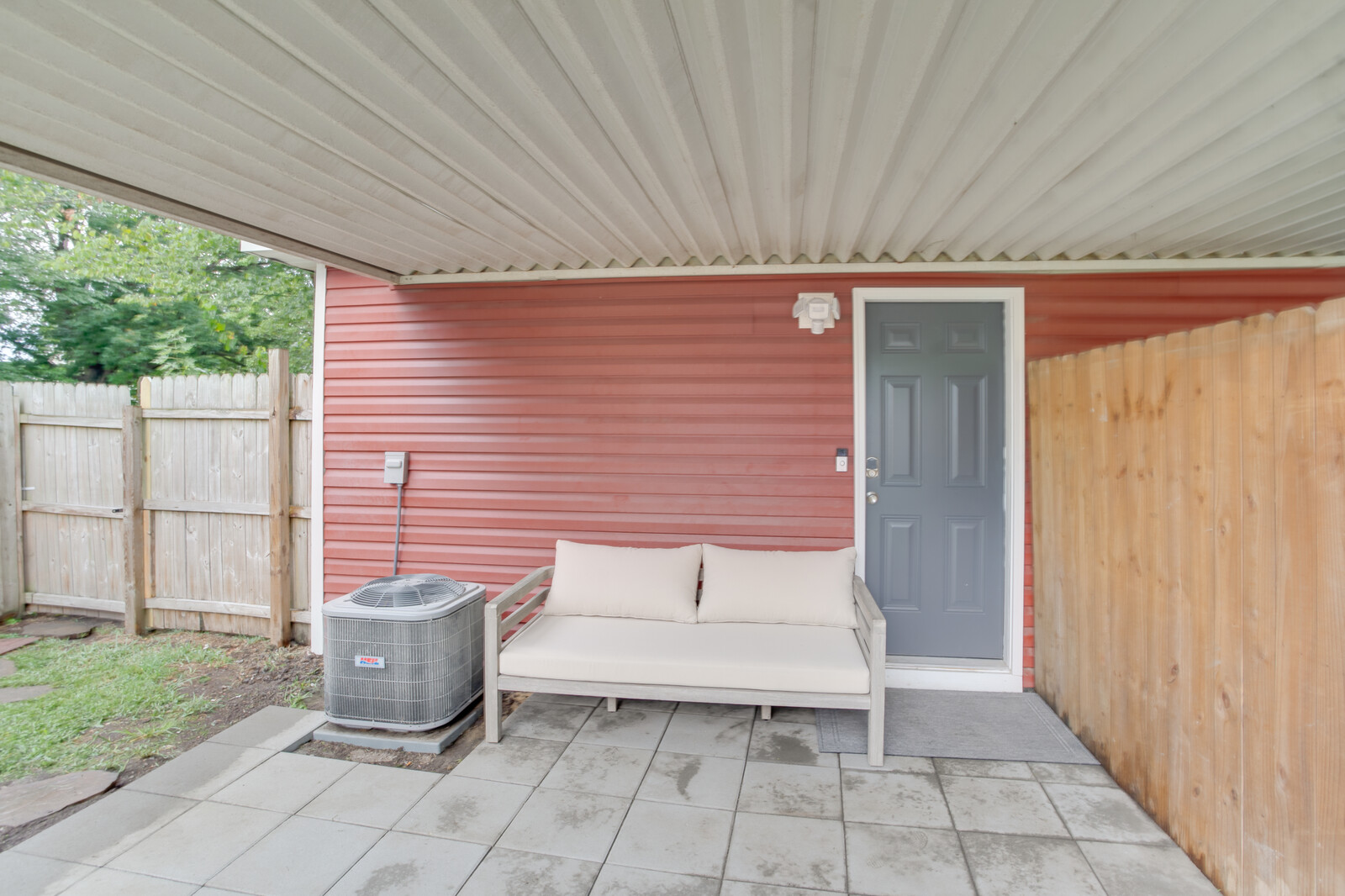 Covered patio area with a cozy outdoor bench and private entrance