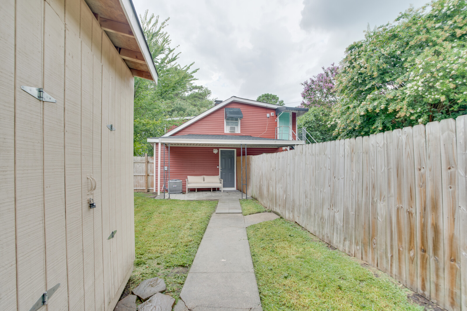 Backyard view with a red house, fenced yard, and outdoor seating