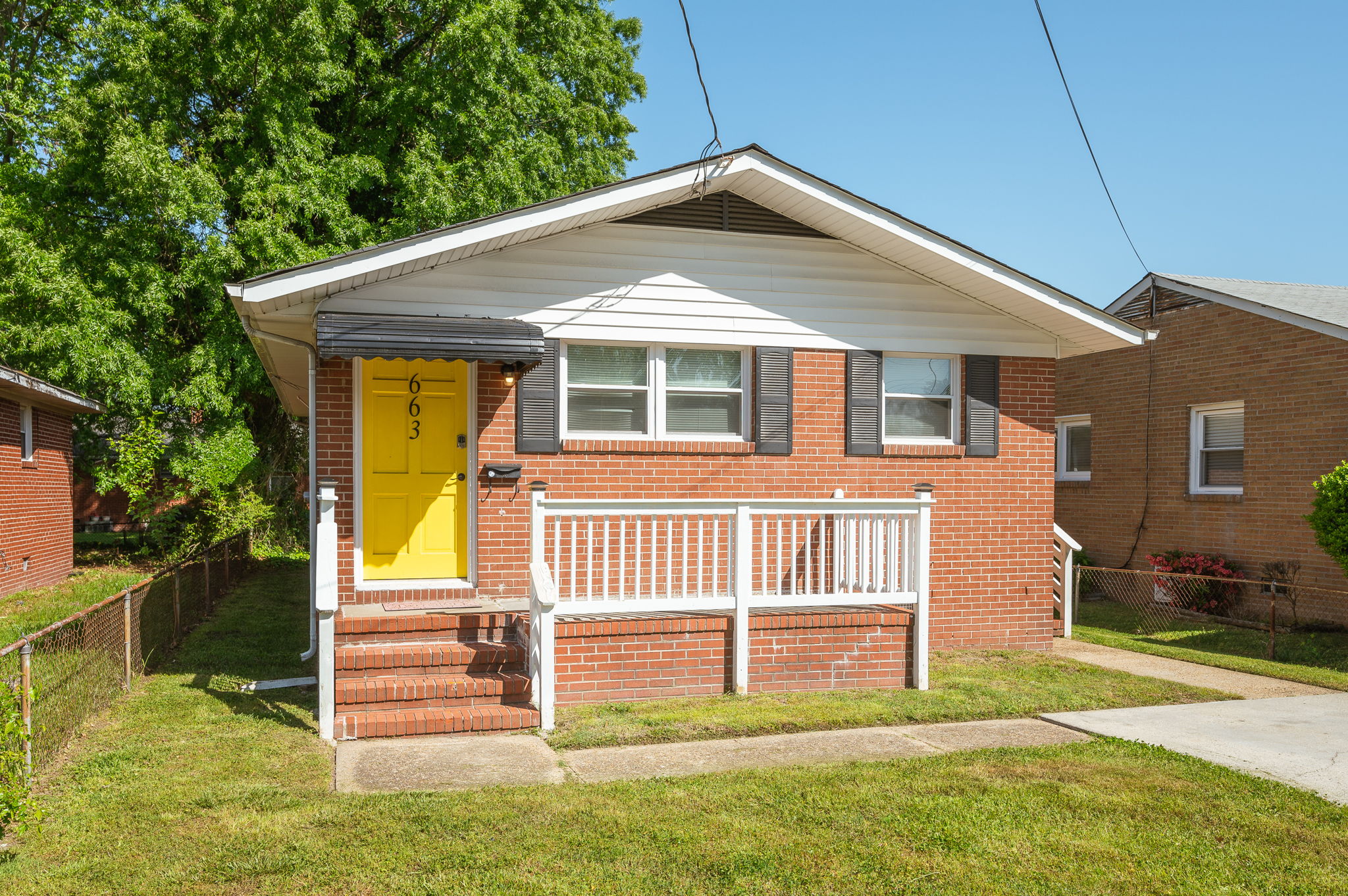 Close-up of the front entrance of a red brick house with a bright yellow door and house number 663.