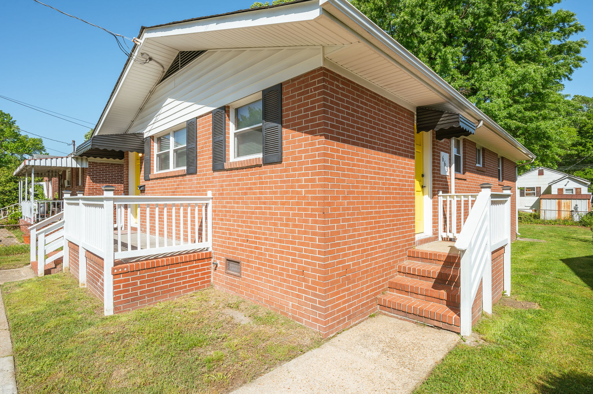 Side angle view of the brick house with white railings and stairs leading to the entrance.