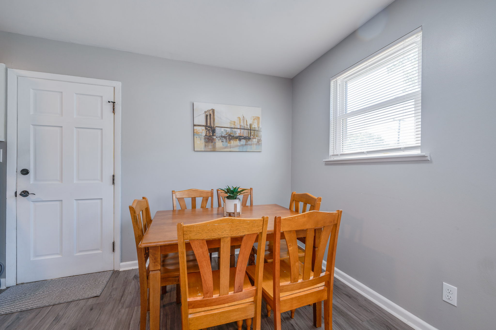 Dining area with a wooden table and six matching chairs next to a bright window.