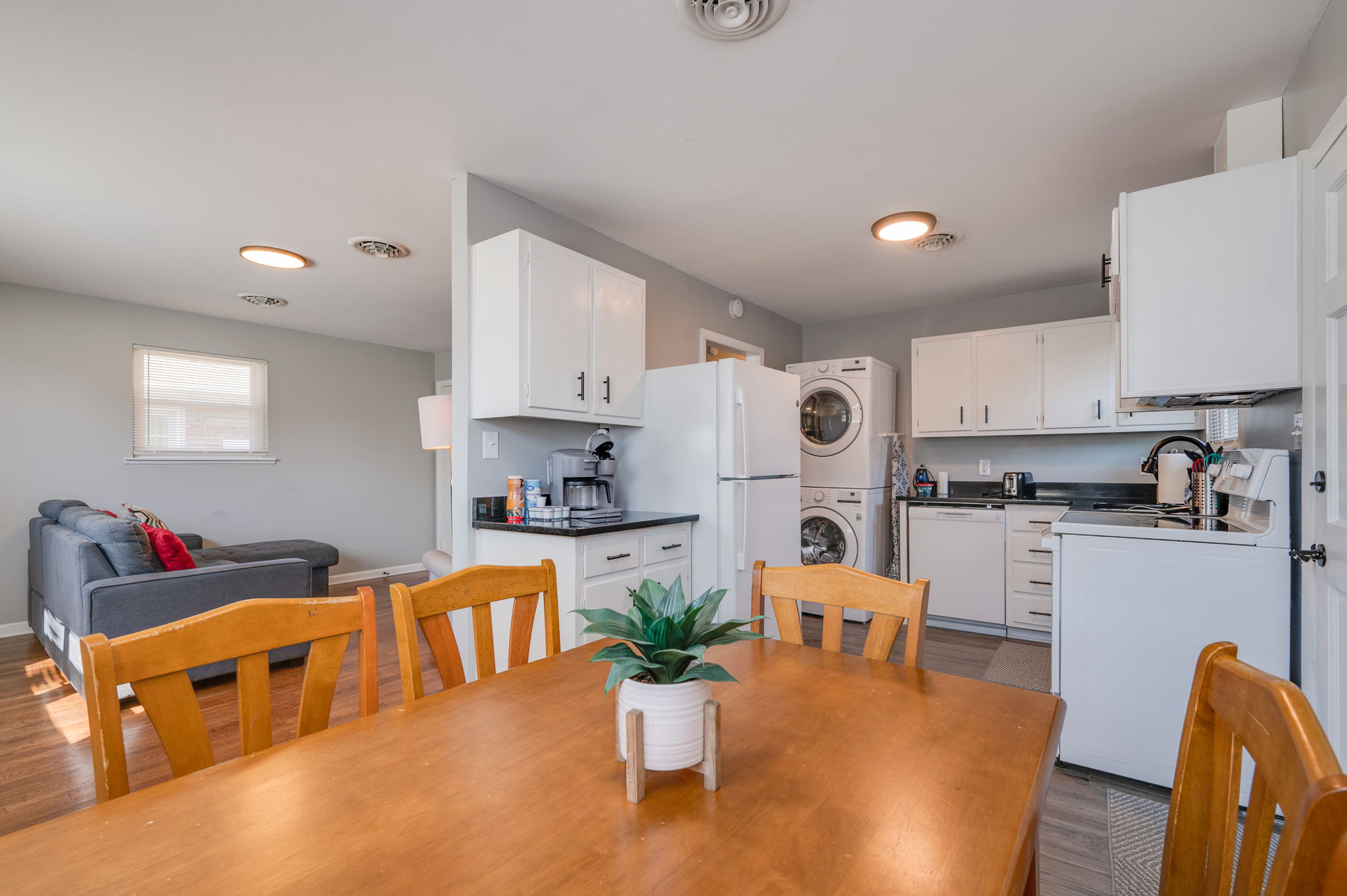 Open-concept kitchen and dining area with a white fridge, washer-dryer, and wooden dining set.
