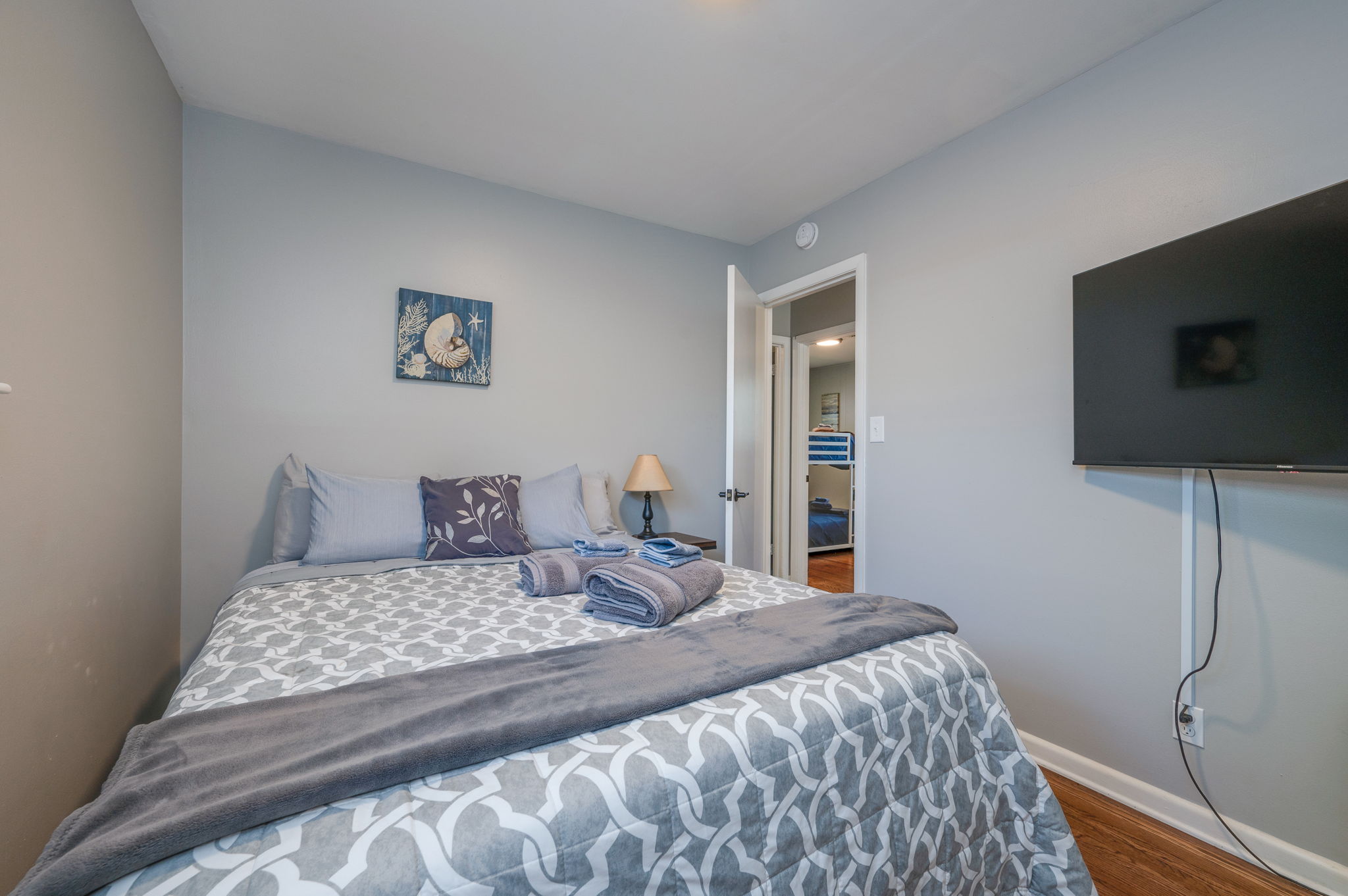 Cozy bedroom with a gray bedspread, decorative pillows, and a wall-mounted TV.