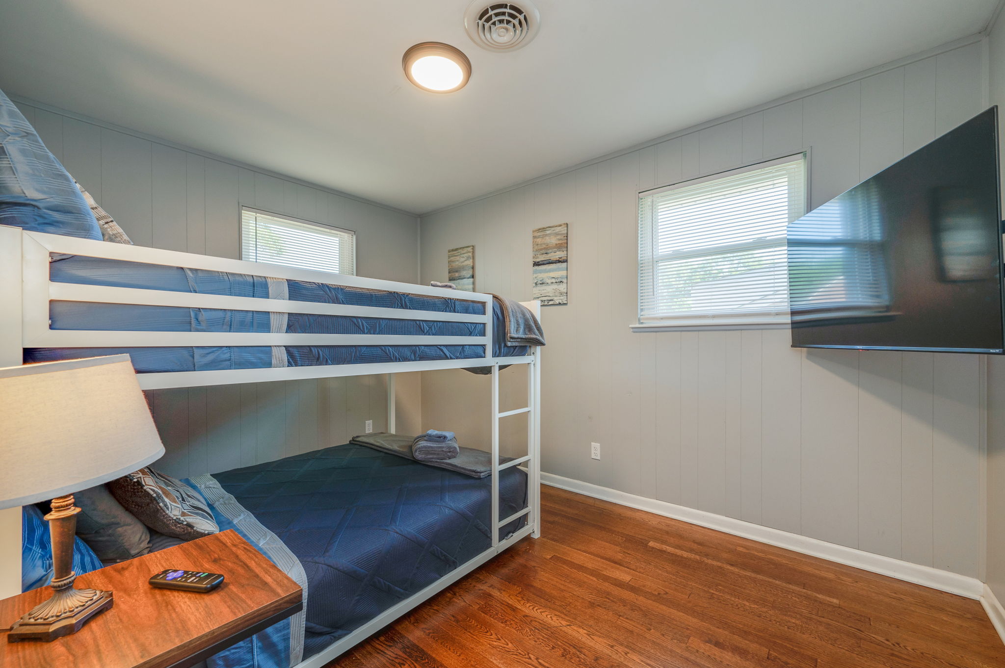 Bedroom with a bunk bed setup, blue bedding, and a mounted flat-screen TV.