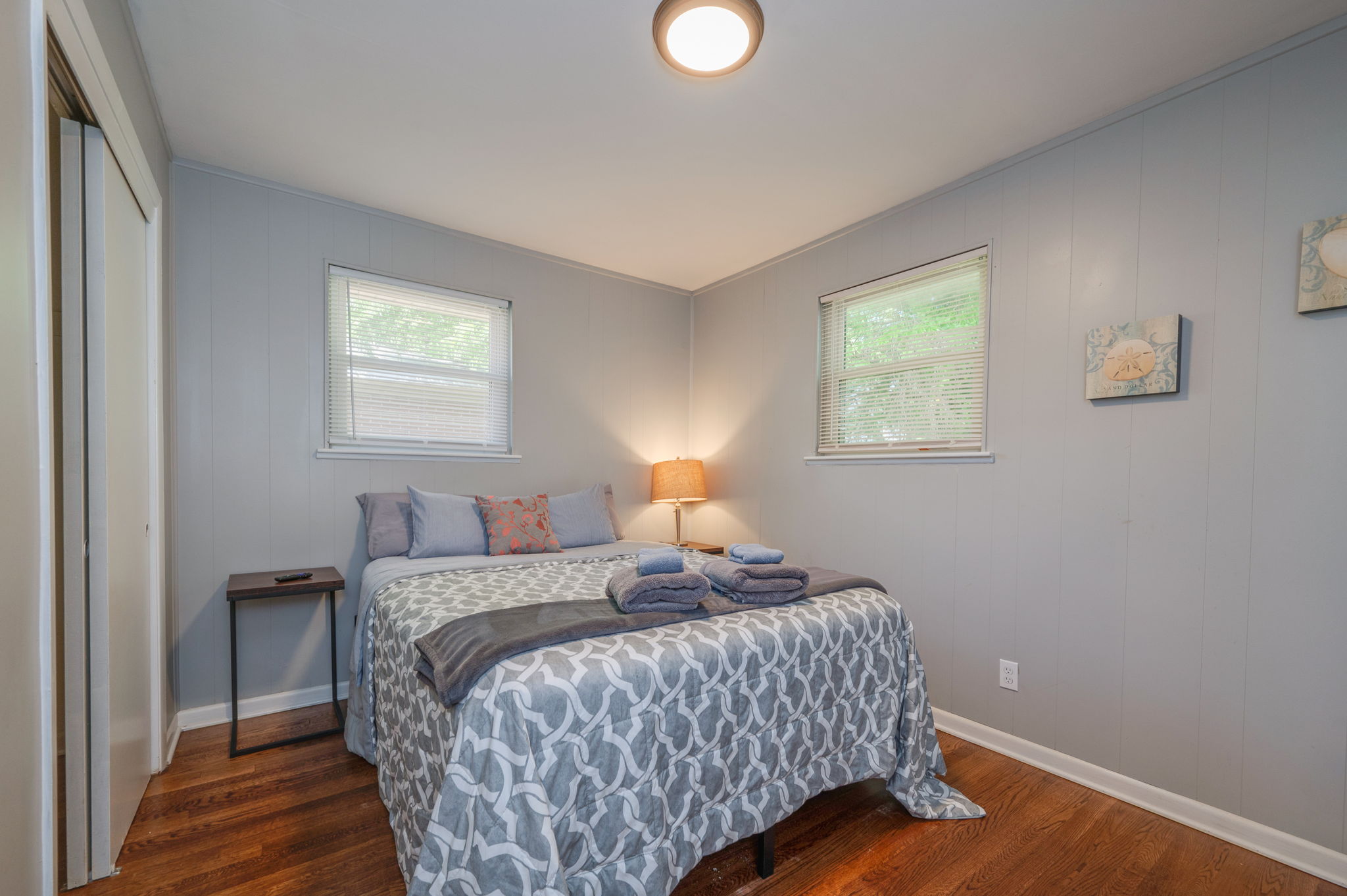 Master bedroom with a queen-size bed, soft gray bedding, and warm bedside lighting.