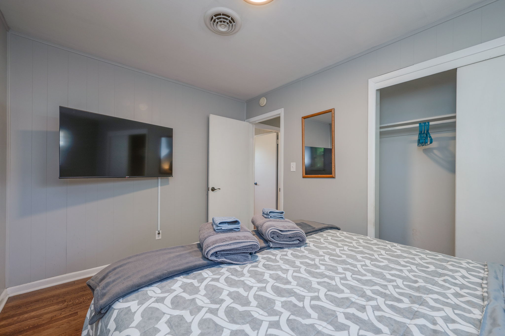 Spacious bedroom with a flat-screen TV, an open closet, and a cozy ambiance.