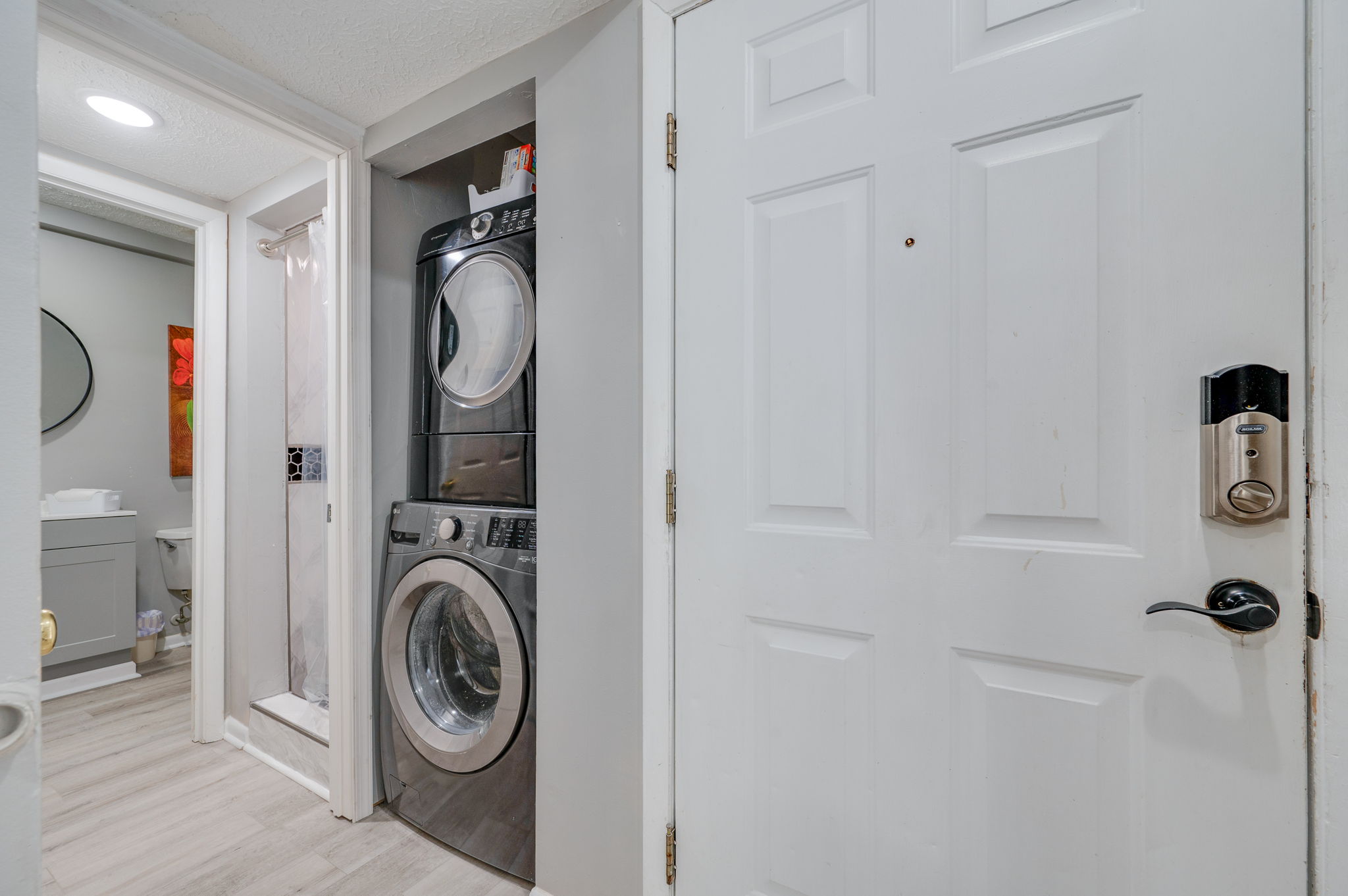 Laundry area with stacked washer and dryer next to a bathroom