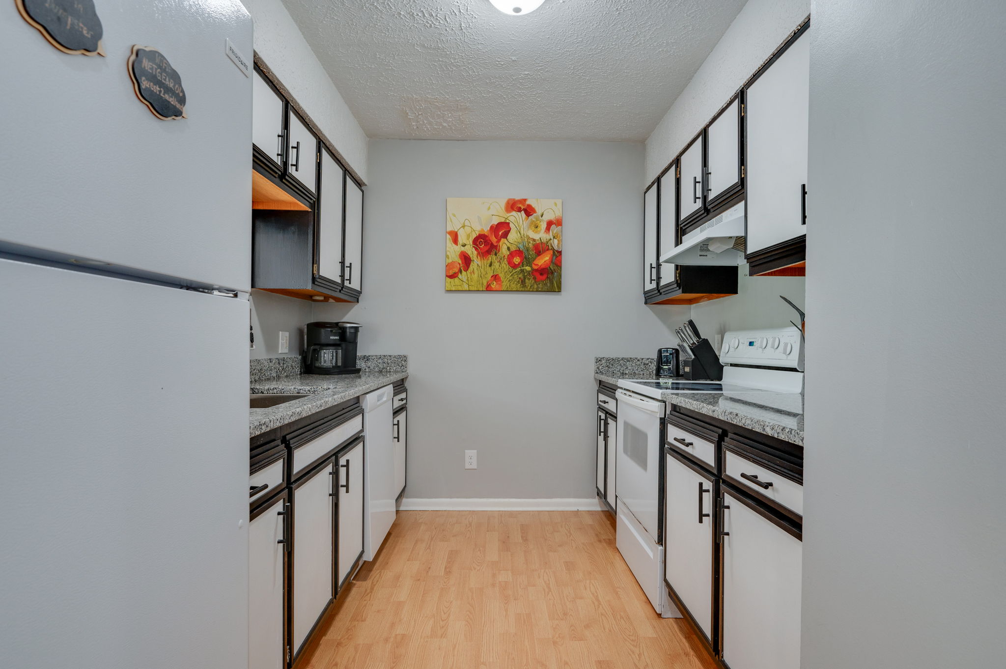 Fully equipped kitchen with white appliances and dark cabinetry
