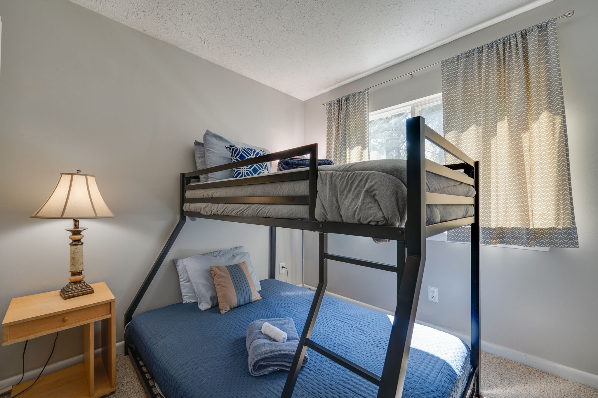 Bedroom with modern black bunk bed and cozy blue bedding