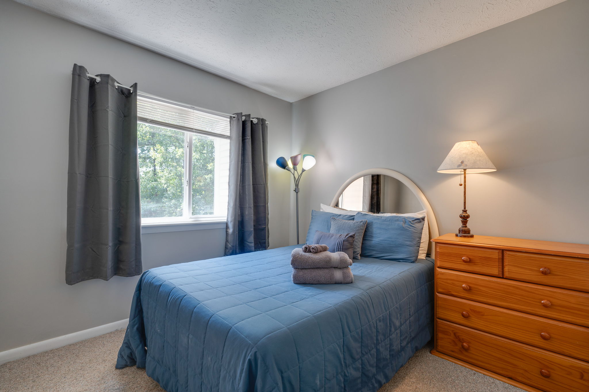 Bedroom with queen bed, blue bedding, and wooden dresser